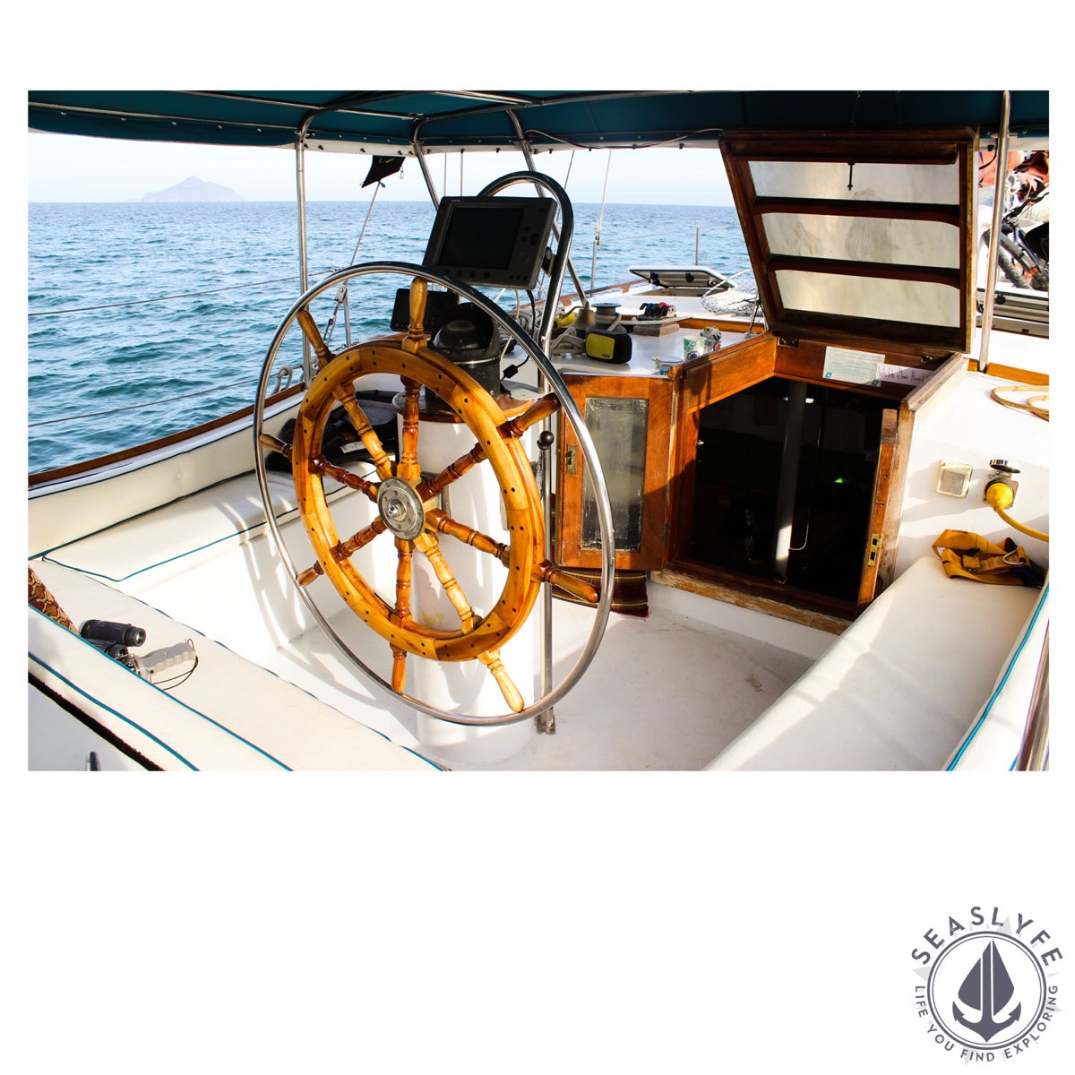 Wood-wheel helm station aboard Seas Lyfe with Simrad electronics